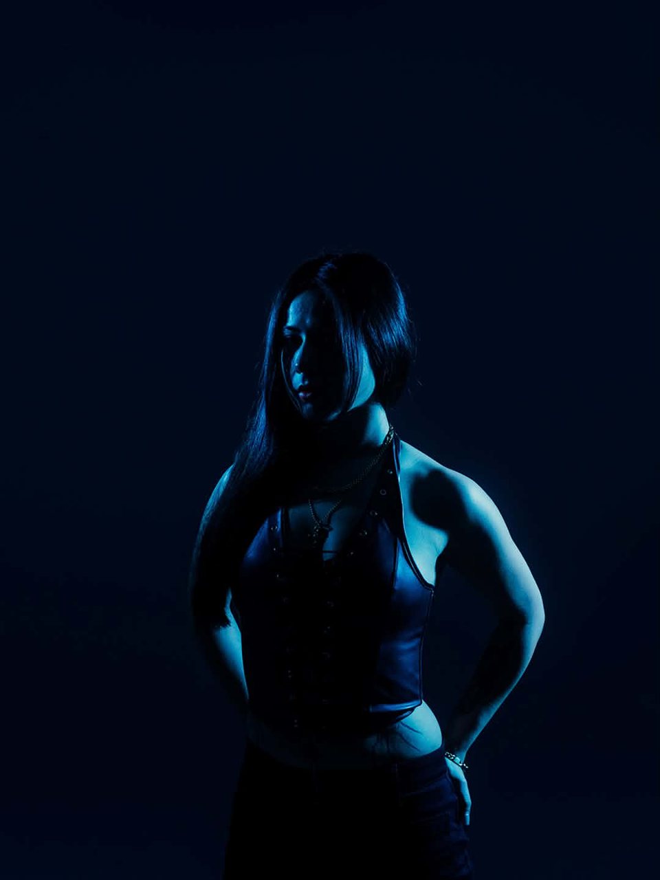 LilyannaMarie lit from one side against a near-black blue backdrop.