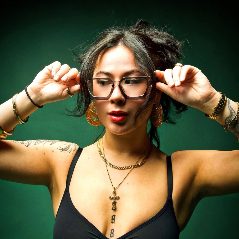 LilyannaMarie in the studio, hands to her glasses.
